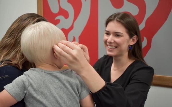 Audiology student fitting child with hearing aid