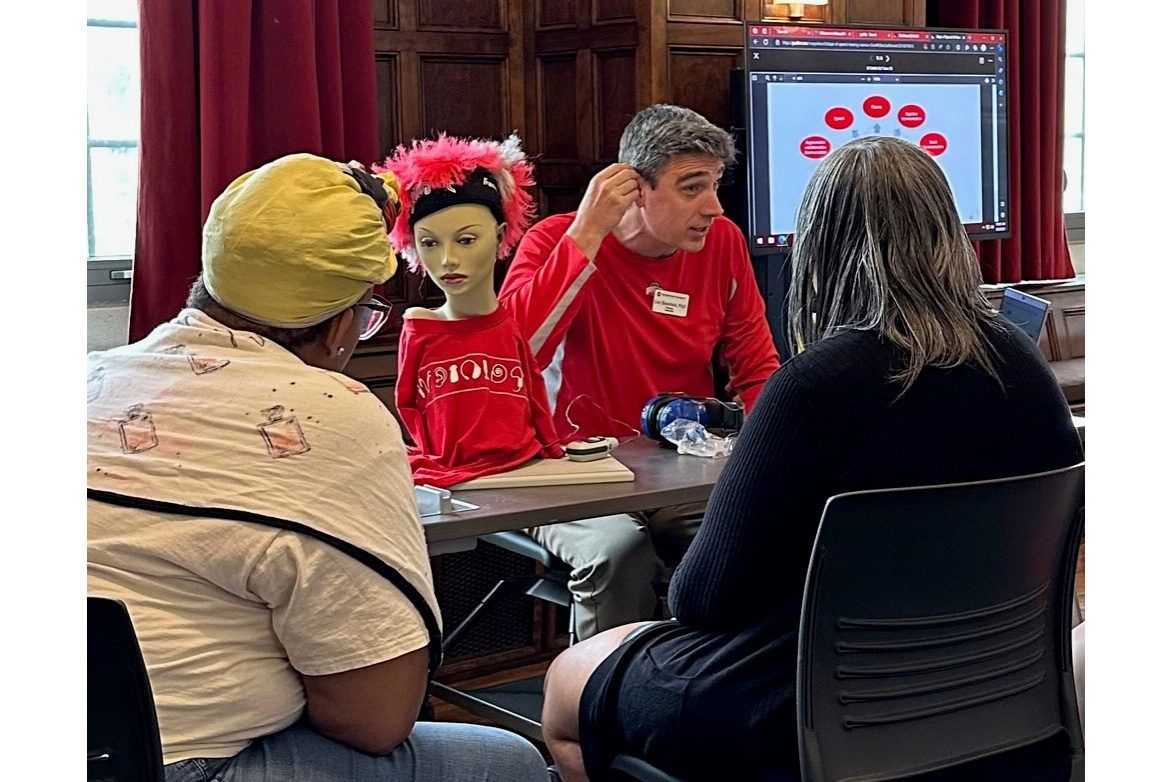 Eric Bielefeld demonstrating hearing aids for 2 participants