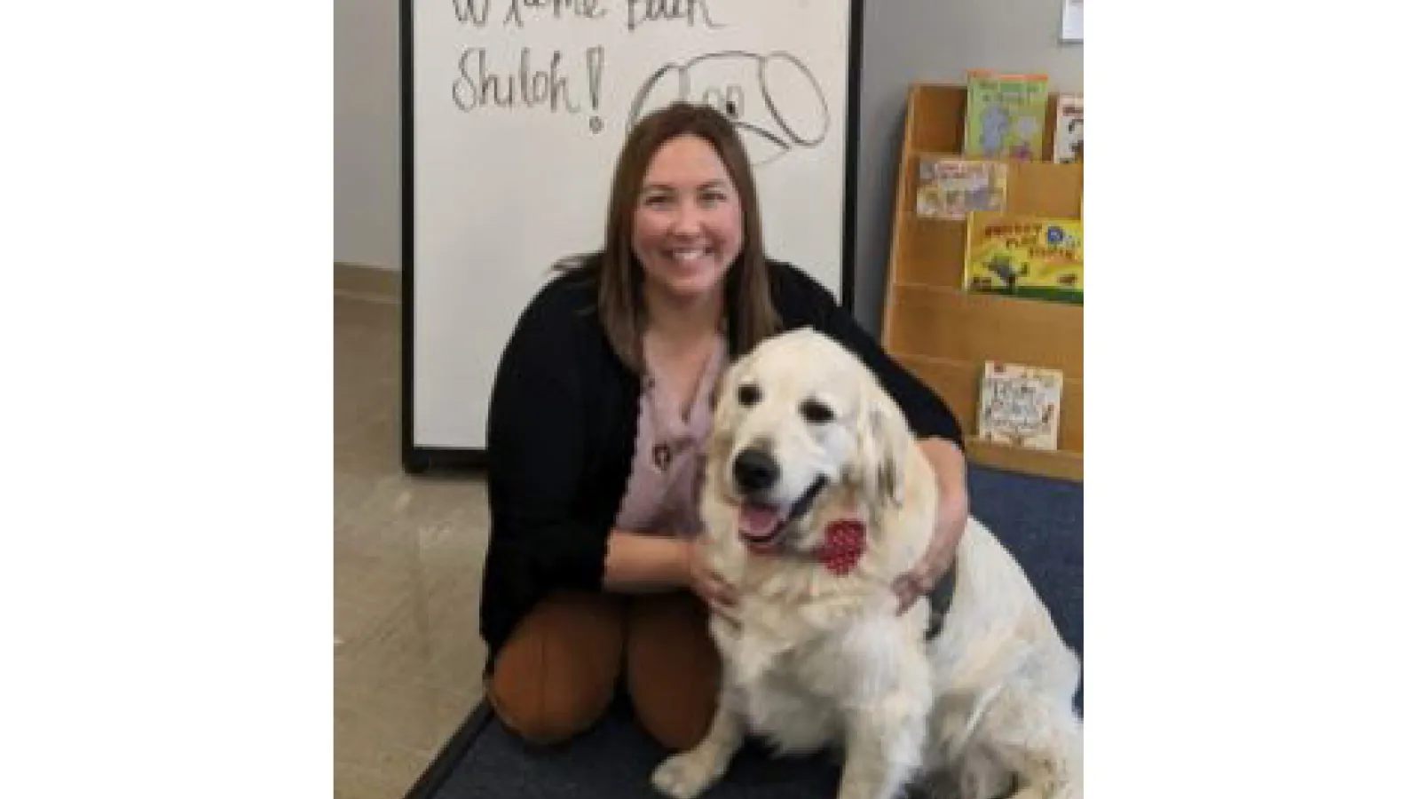 Bridget Chapman posing with Shiloh, a cream retriever dog wearing a red bowtie