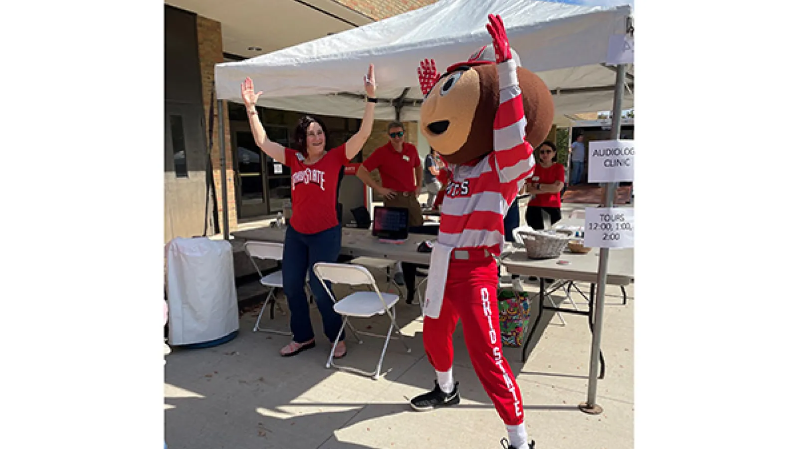 Brutus posing with faculty under tent