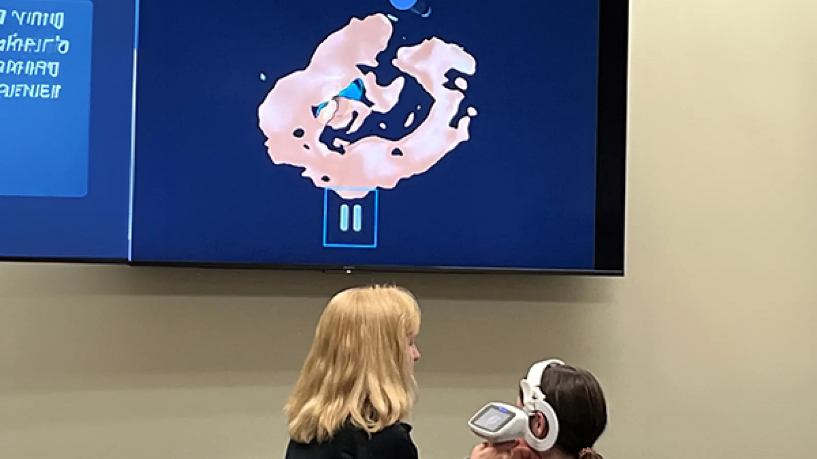 Christy Goodman using Otoscan device on patient with scanned image displayed on large screen