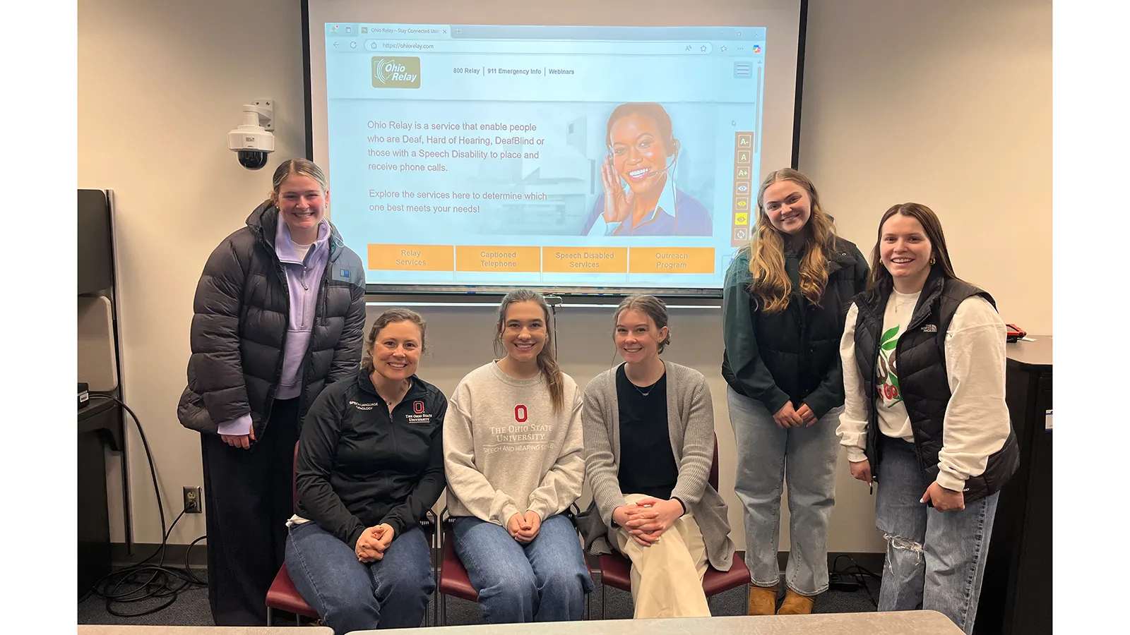 Students and instructor posing in front of presentation screen