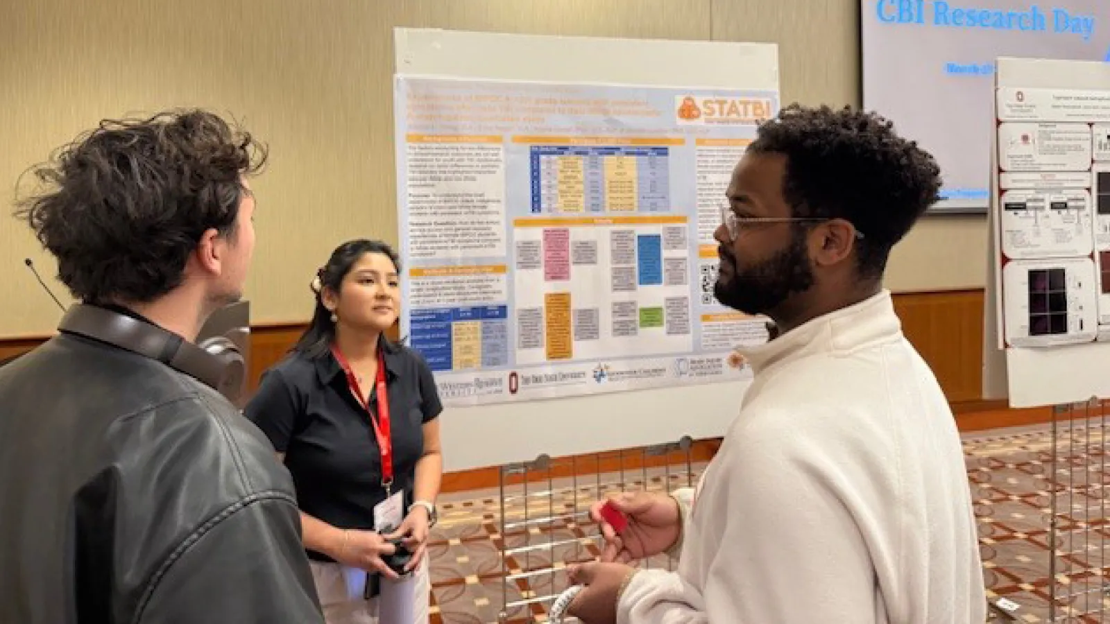 Students engaged in conversation in front of research poster
