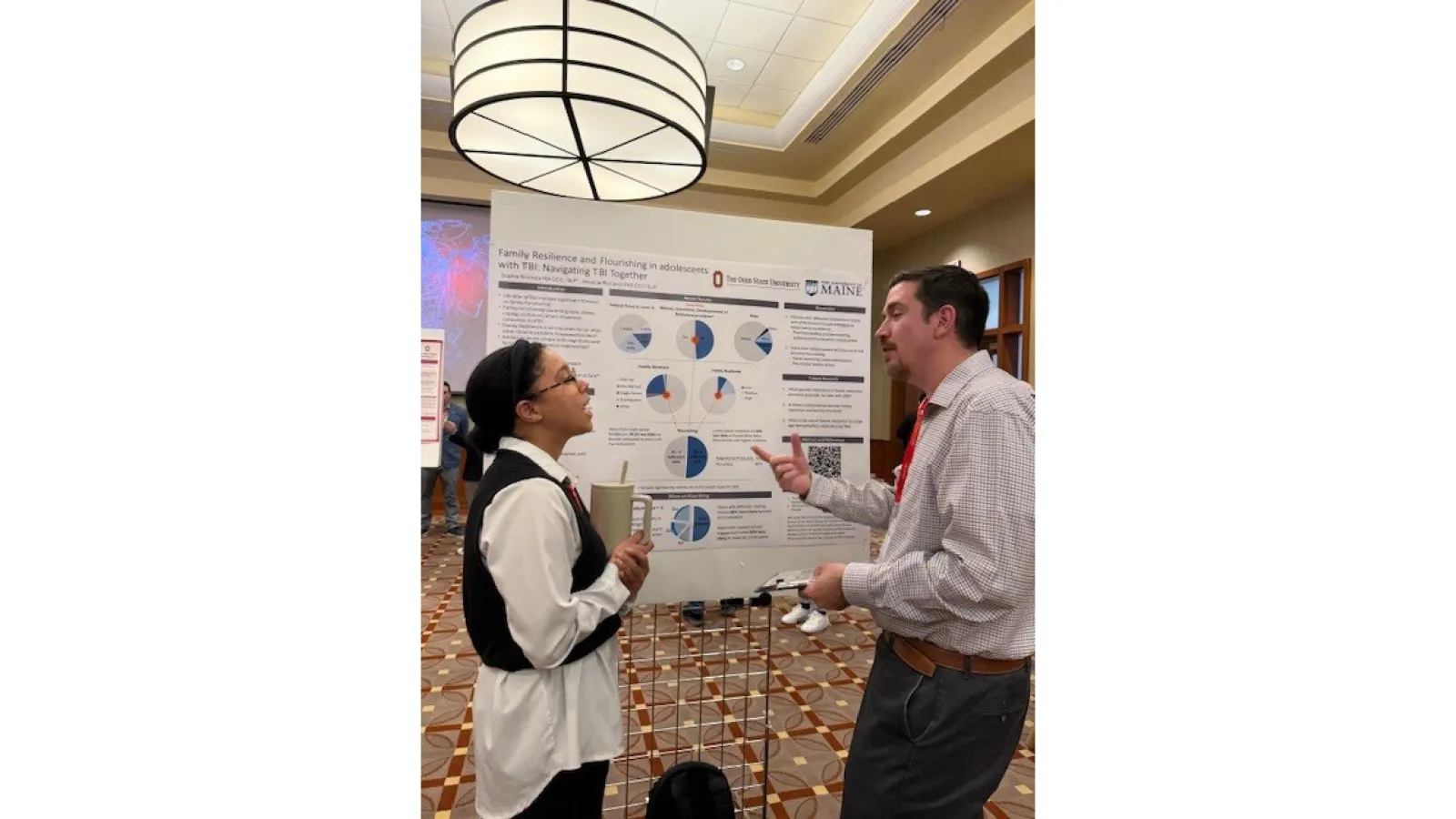 Two people engaging in conversation in front of research poster
