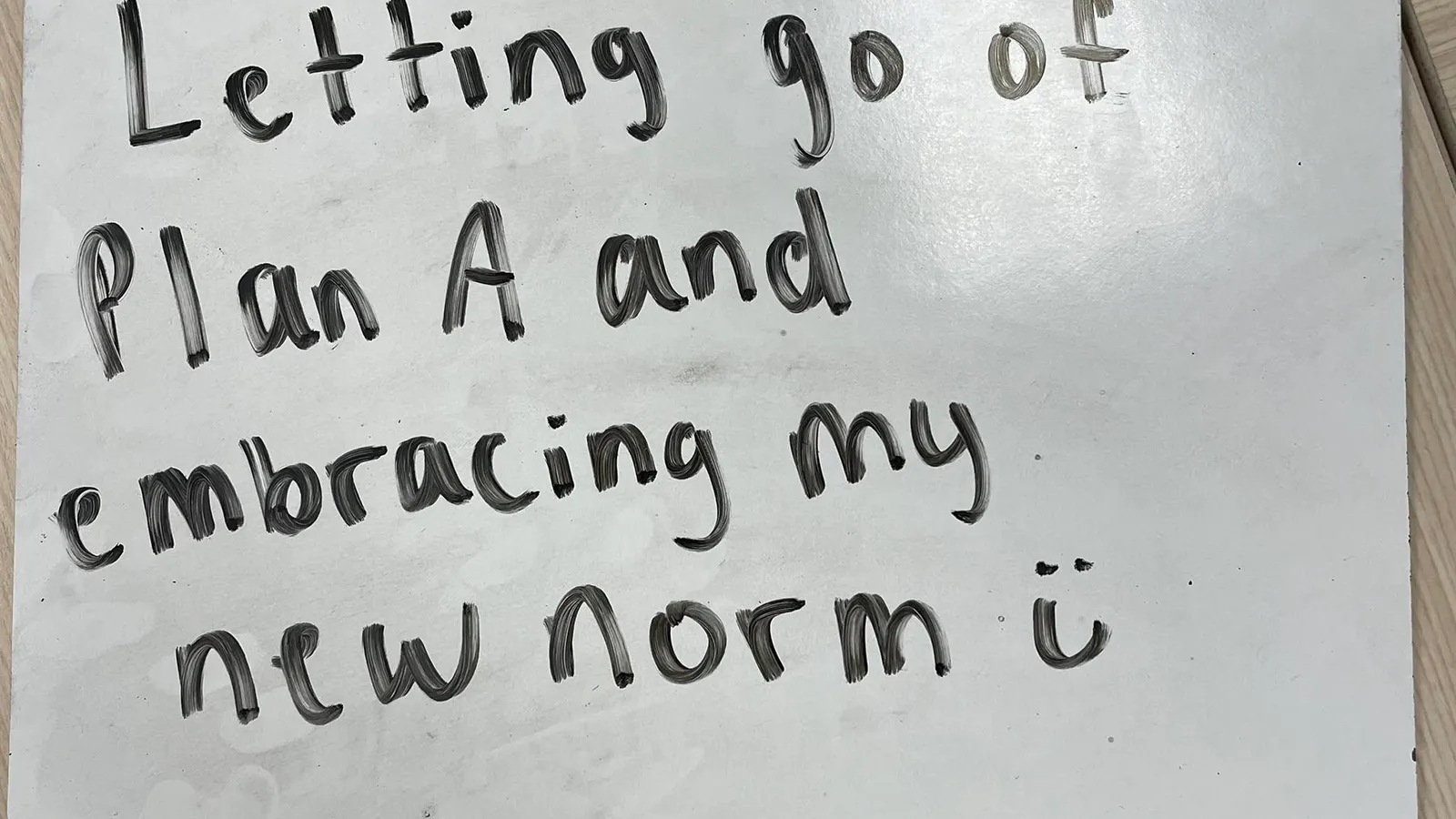 Black writing on whiteboard "Letting go of Plan A and embracing my new norm :)"