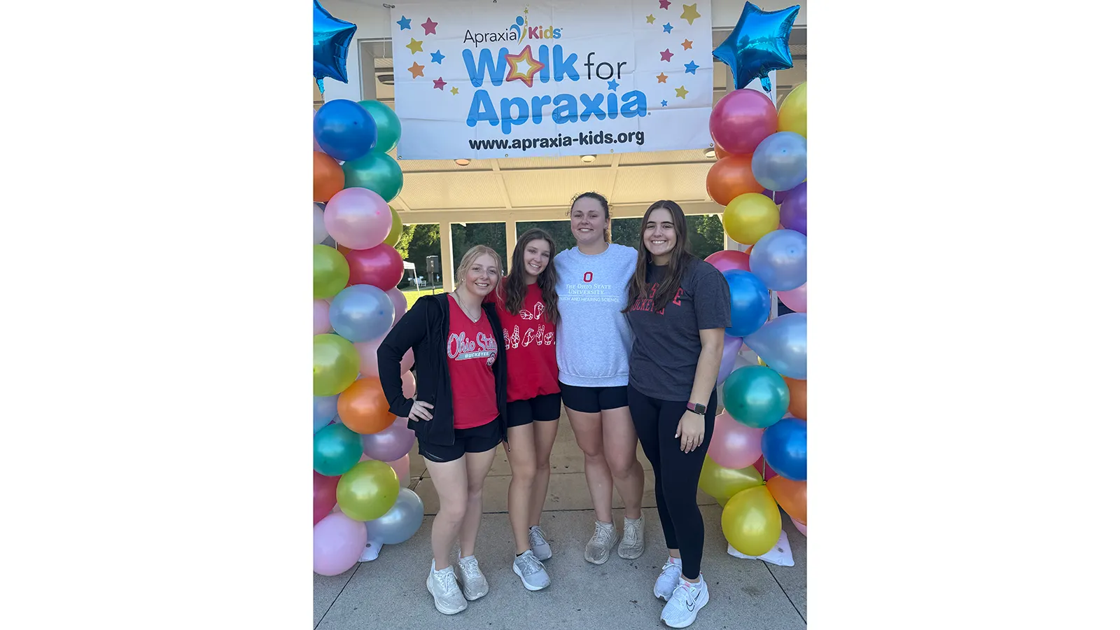 Group photo of students with balloon towers and apraxia sign