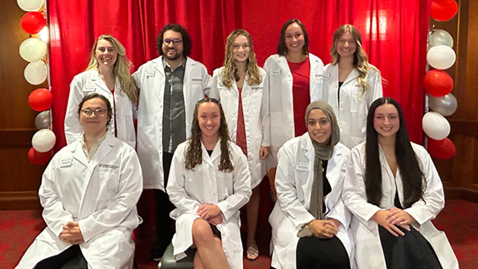 Group photo of 9 students in white coats