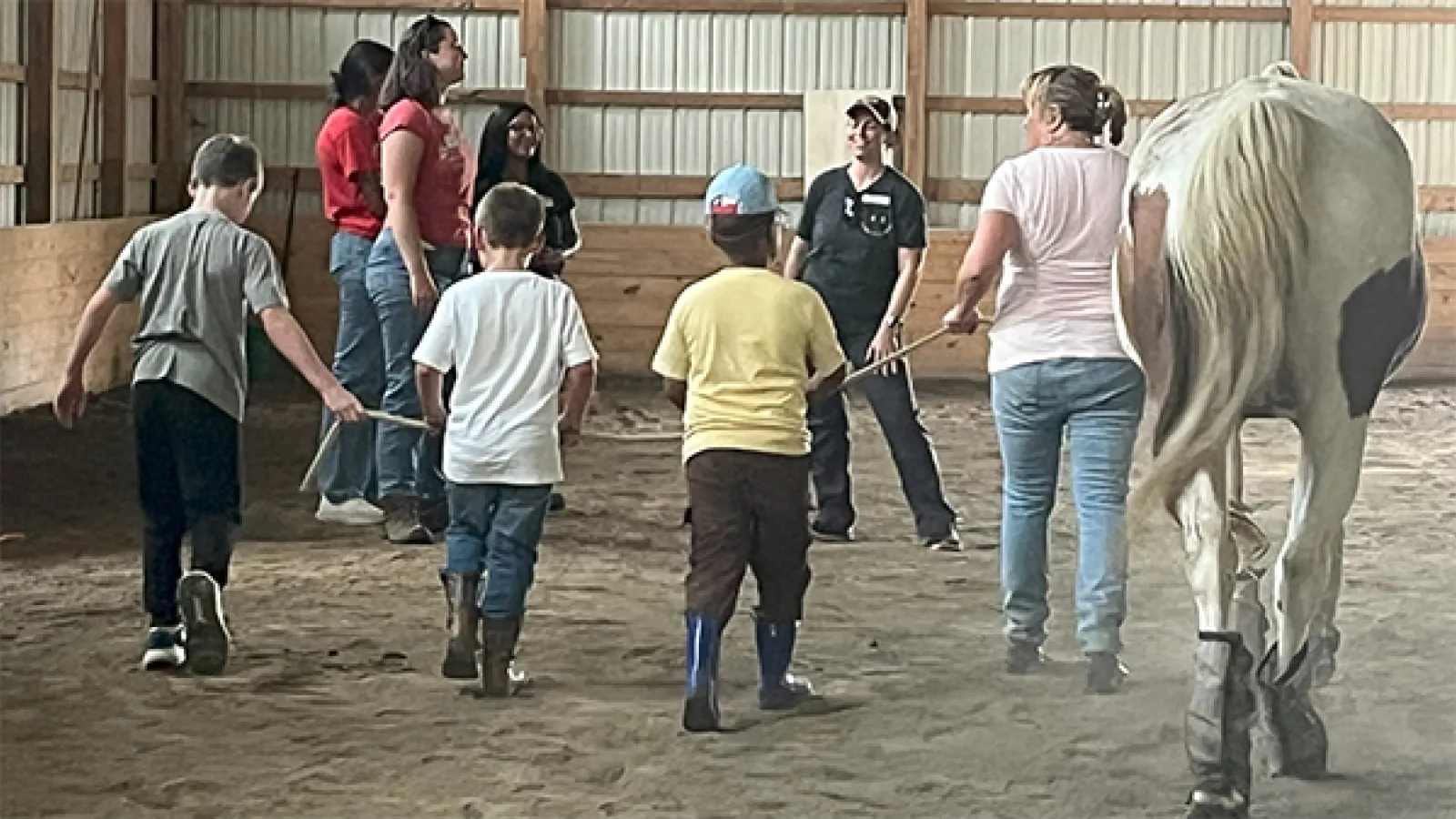 group of children and adults working with a horse