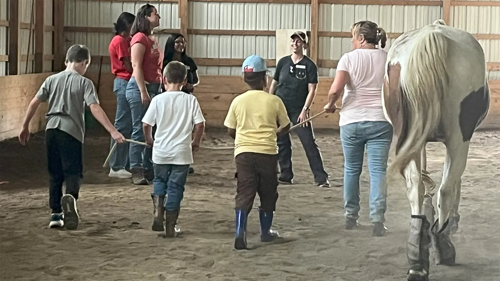 children and adults leading a horse around barn 