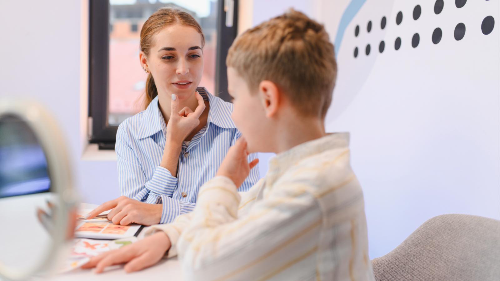 Young boy receiving speech therapy with a female therapist 