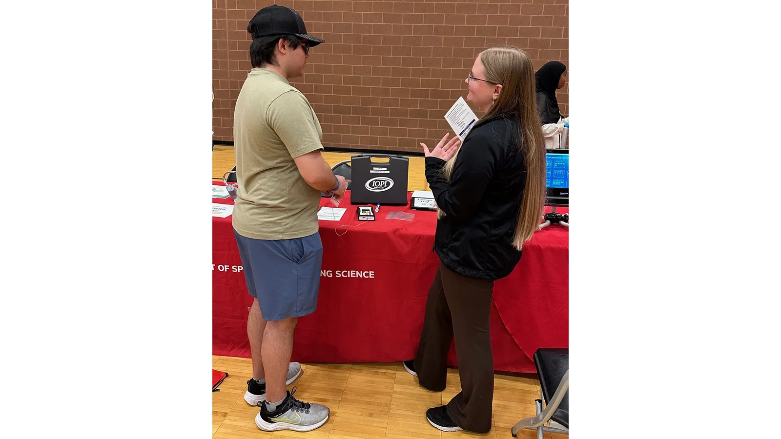 Graduate student chatting with a young person at table display
