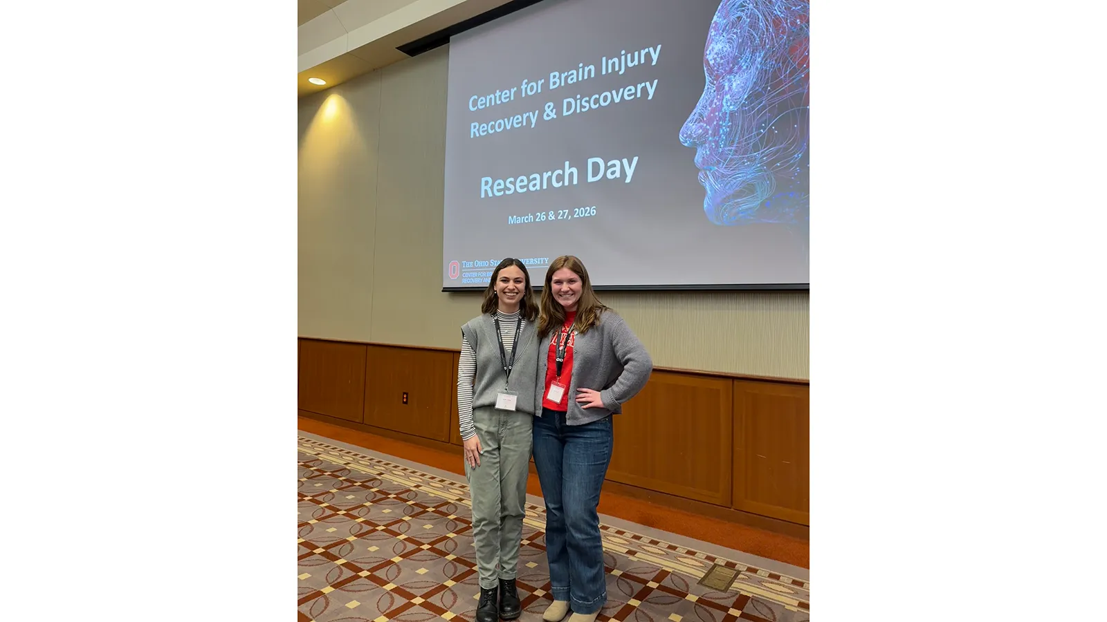 Natalie Freitag and Grace Terry posing in front of presentation screen