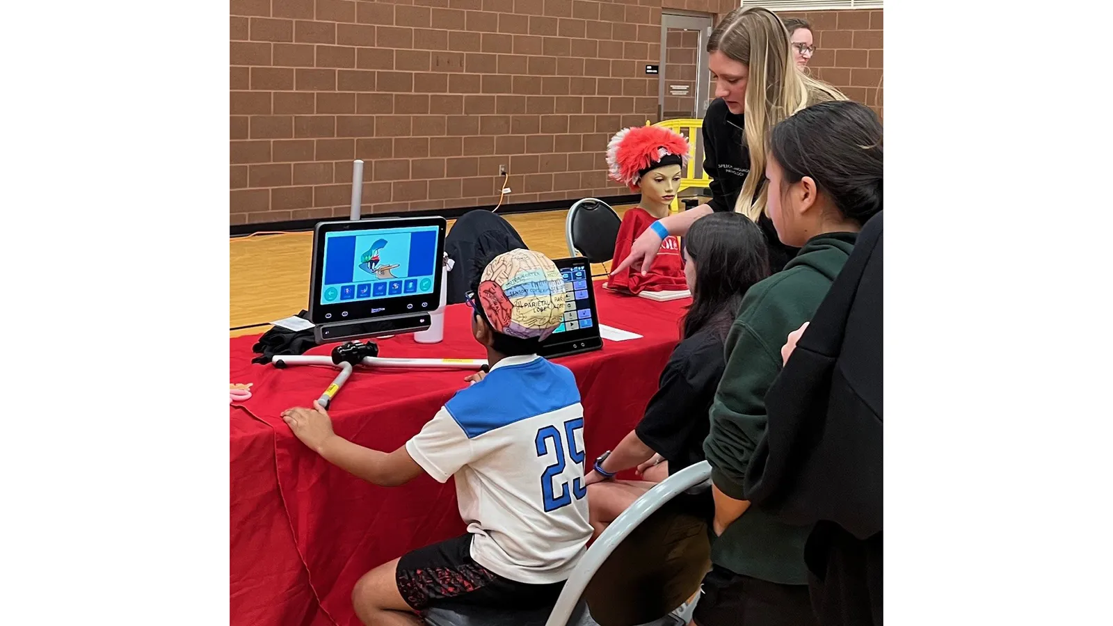 young person with cap modeling brain seated at computer