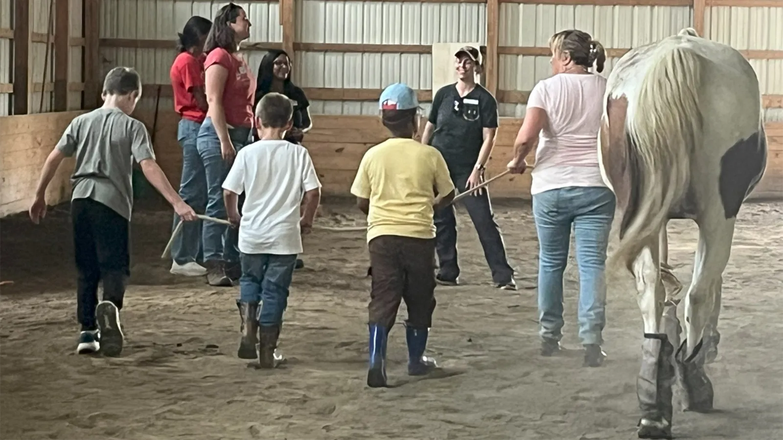 children and adults leading horses around a ring