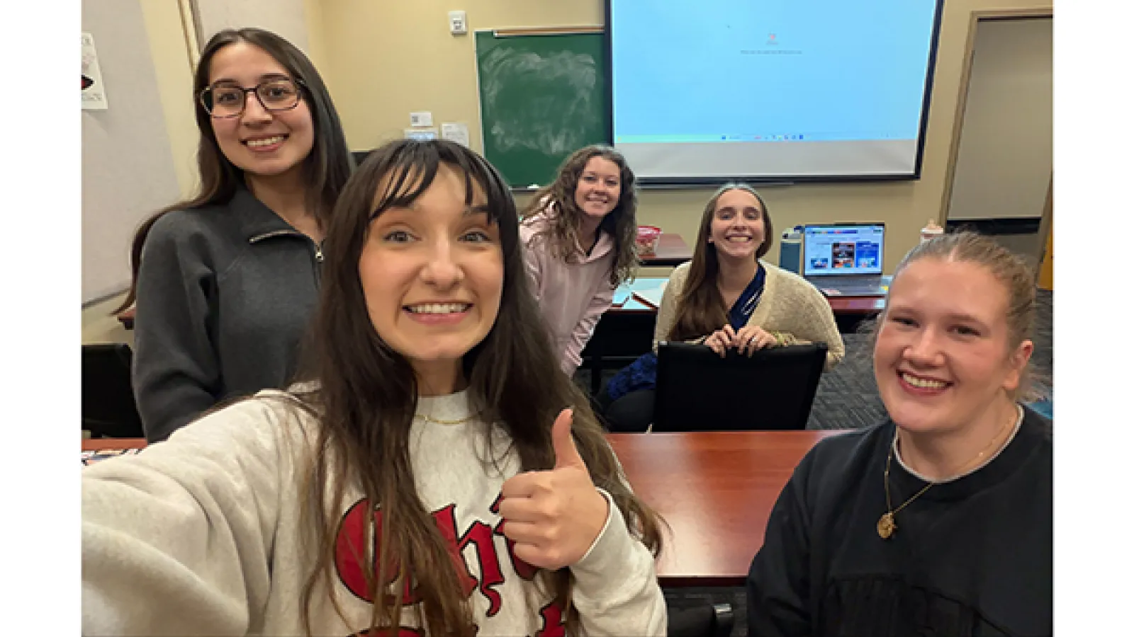 Group selfie of students giving thumbs up