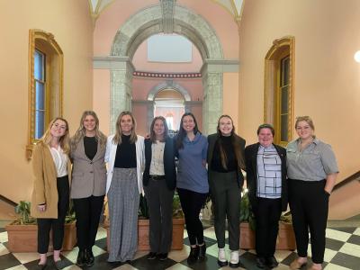 Group picture of 6 students and 2 faculty in statehouse