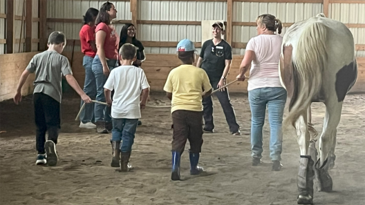 children and adults leading horses around a ring