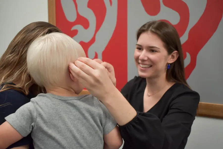 Audiology student fitting child with hearing aid