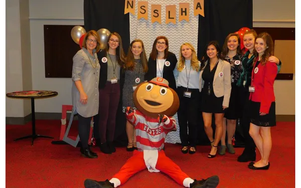 Group photo of students and faculty with Brutus in banquet setting