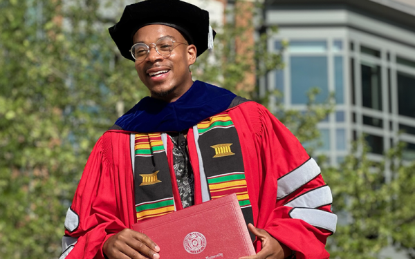 PhD student in regalia with diploma