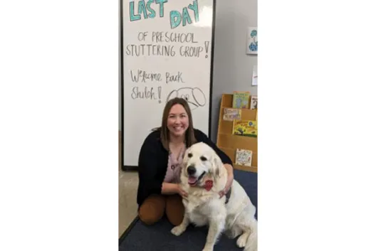 Bridget Chapman posing with Shiloh, a cream retriever dog wearing a red bowtie