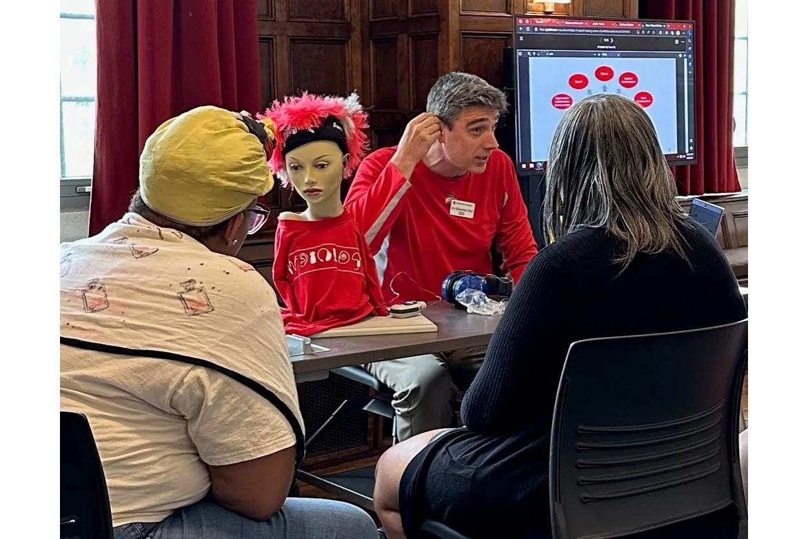 Eric Bielefeld demonstrating hearing aids for 2 participants