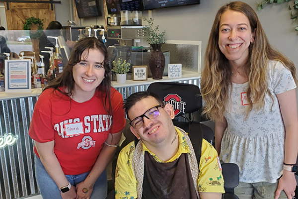 Shea, Brady, and Alexa pose in front of coffee shop counter