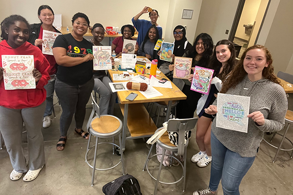 Group photo of students holding up artwork