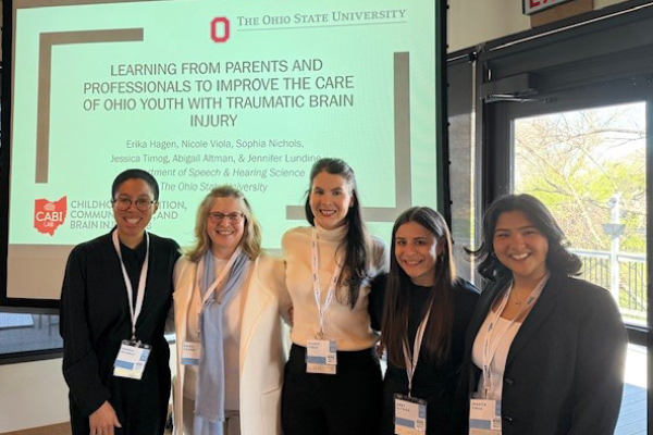 Five students posing in front of presentation screen