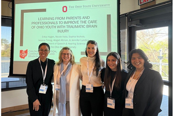 5 students posing in front of presentation screen