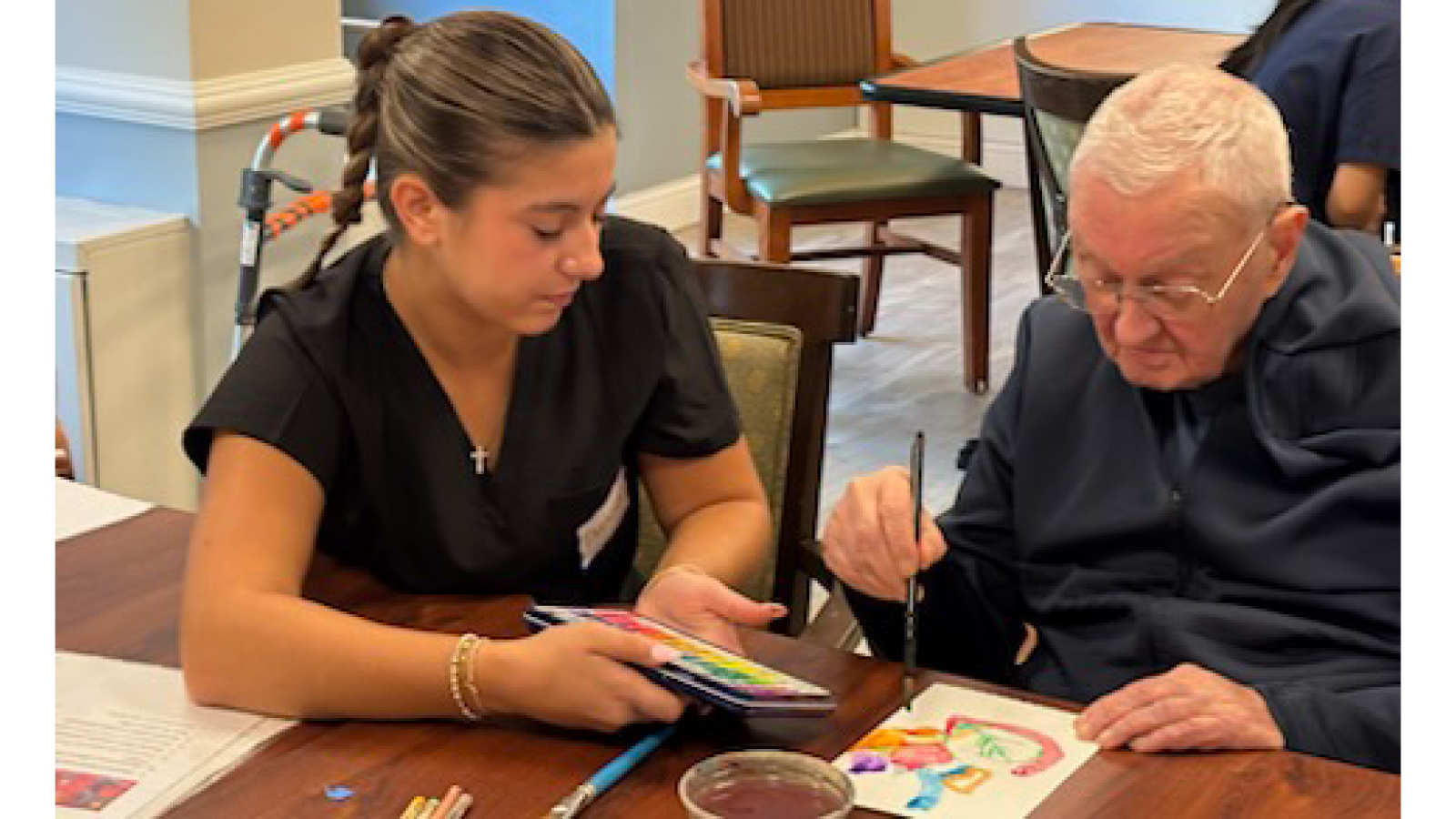 student in scrubs paints with patient