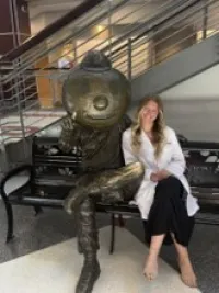 Audrey Corder seated next to Brutus statue
