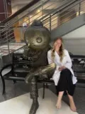 Audrey Corder seated next to Brutus statue